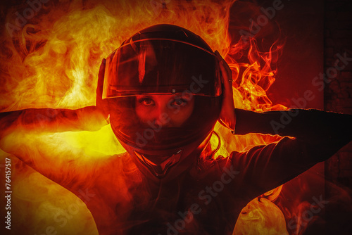 Young beautiful girl in the motorbike helmet on the fire smoke background. Street racing concept.
