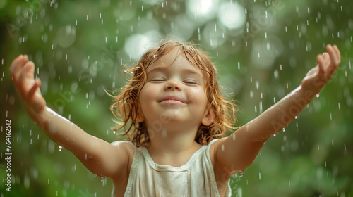 a child who raises his hands and catches the rain with his palms, the emotion of pleasure and enjoyment of the moment of life is on his face photo