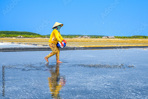 A woman is spreading salt to stimulate salt crystallization on her salt field in Can Gio district, a suburban district of Ho Chi Minh City, Vietnam.