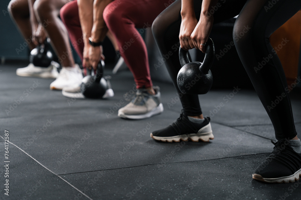 People squatting with kettlebells for leg exercise at gym