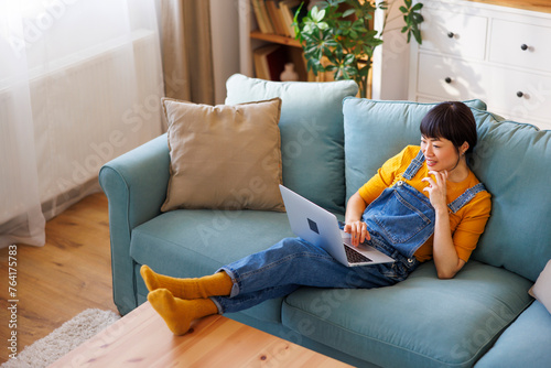 Woman using laptop computer while relaxing at home