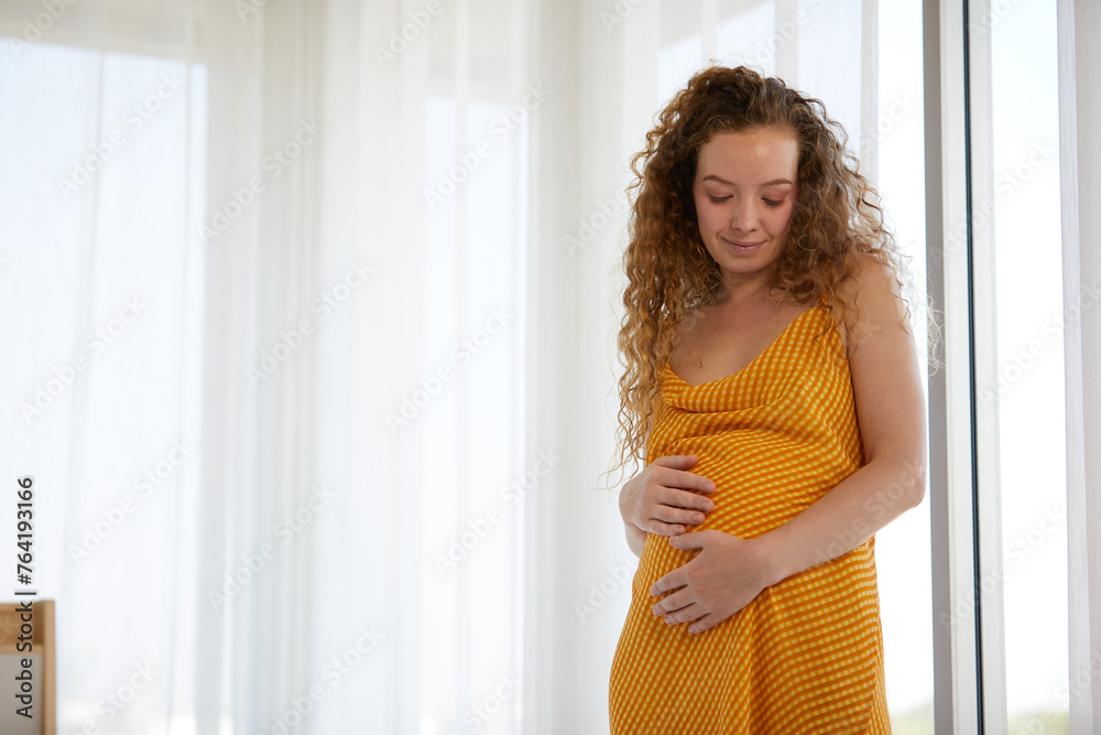 pregnant woman smiling and relaxing in the bedroom