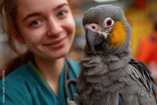 Smiling young veterinary assistant with a colorful grey parrot perched on her shoulder in an animal clinic