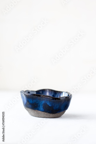 A white ceramic bowl made of black clay, covered with a sea-green glaze on a white background. Isolated.