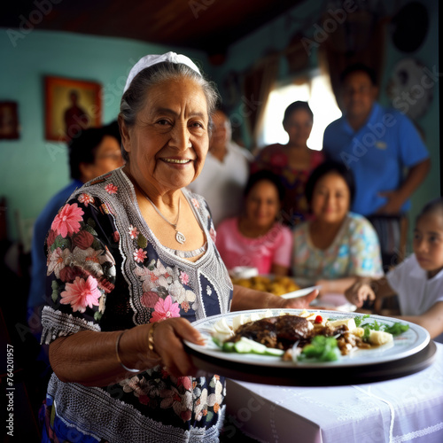 joyous elderly woman standing by the dinner table between her seated family members Hispanic American.