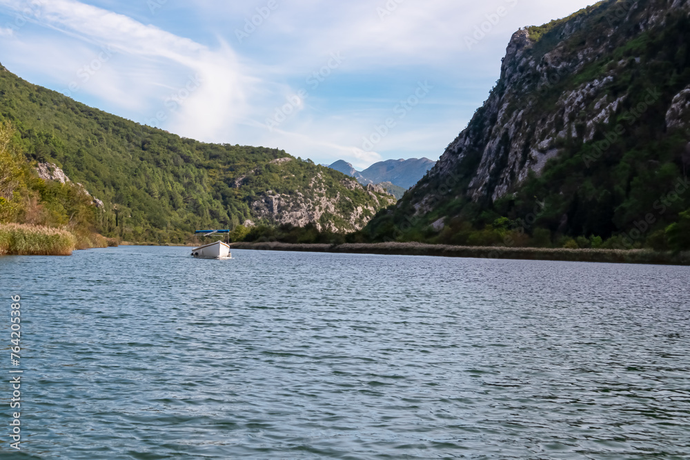 Boat on cetina river merging with Adriatic Sea in coastal town Omis, Split-Dalmatia, Croatia, Europe. Idyllic gorge surrounded by steep Dinara mountains. Majestic coastline of Omis Riviera. Balkans