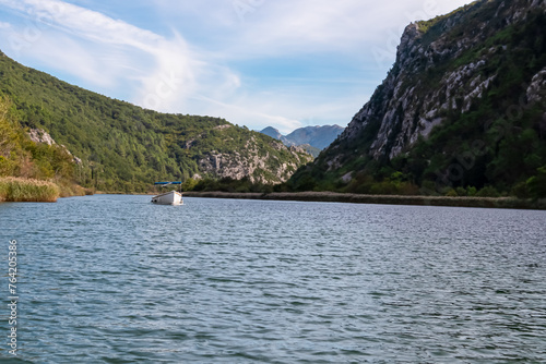 Boat on cetina river merging with Adriatic Sea in coastal town Omis, Split-Dalmatia, Croatia, Europe. Idyllic gorge surrounded by steep Dinara mountains. Majestic coastline of Omis Riviera. Balkans
