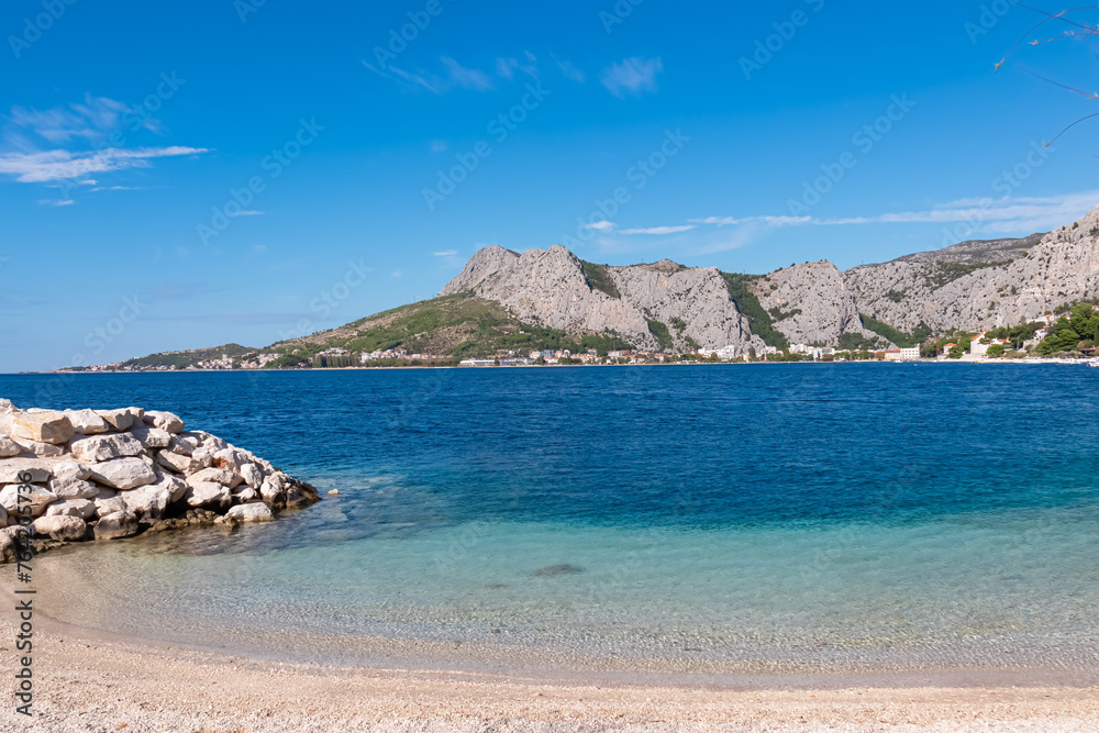 Idyllic sand beach Plaza Brzet in coastal town Omis, Split-Dalmatia, Croatia, Europe. Scenic view of majestic mountains of Dinaric Alps, Balkans. Adriatic Mediterranean Sea in summer. Vacation concept