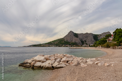 Idyllic sand beach Plaza Brzet in coastal town Omis, Split-Dalmatia, Croatia, Europe. Scenic view of majestic mountains of Dinaric Alps, Balkans. Adriatic Mediterranean Sea in summer. Vacation concept photo