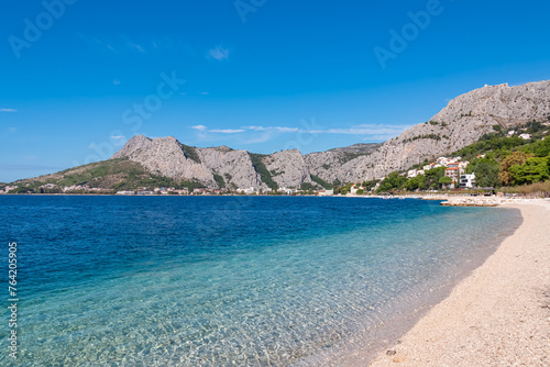 Idyllic sand beach Plaza Brzet in coastal town Omis, Split-Dalmatia, Croatia, Europe. Scenic view of majestic mountains of Dinaric Alps, Balkans. Adriatic Mediterranean Sea in summer. Vacation concept