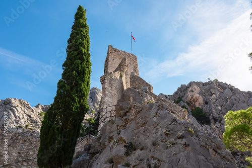 Scenic view of Mirabela Fortress (Peovica) in old town of Omis, Split-Dalmatia, South Croatia, Europe. Stone landmark surrounded by steep Dinara mountains. Ancient fort on rock formation. Tourism photo