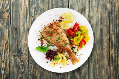 Fried tasty fish dish with vegetable served on plate