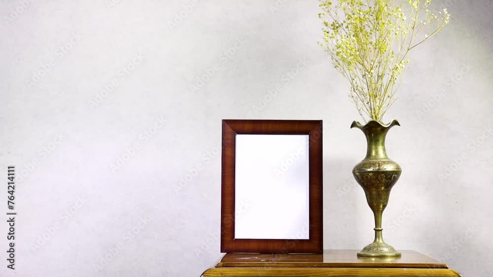 empty picture frame mockup and golden antique metal gypsophila flowers vase on wooden table near grunge wall, autumn fall concept empty picture frame mockup and golden antique metal gypsophila flowers vase on wooden table near grunge wall, autumn fall concept