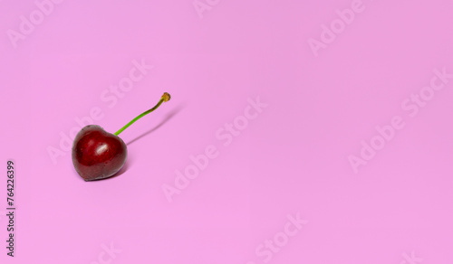 red cherry with a glossy surface and a green stem, its sweet ripeness suggested by its deep red color