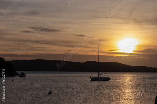Silhouette of sailing boat during romantic sunset in idyllic Kvarner Bay in Medulin, Croatia, Europe. Calm bay of Adriatic Mediterranean Sea. Tranquil peaceful scene. Travel destination in summer © Chris