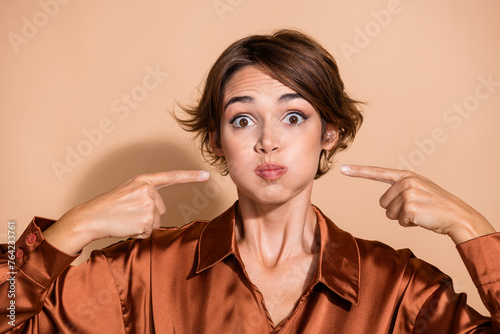 Photo of shocked funky lady dressed silky shirt fingers pressing bloated cheeks isolated beige color background photo