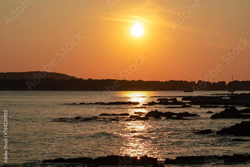 Beautiful sunset at rocky beach in coastal town Medulin, Istria peninsula, Croatia, Europe. Romantic view of rugged coastline Kvarner Gulf in Adriatic Mediterranean Sea in tranquil summer. Tranquility photo
