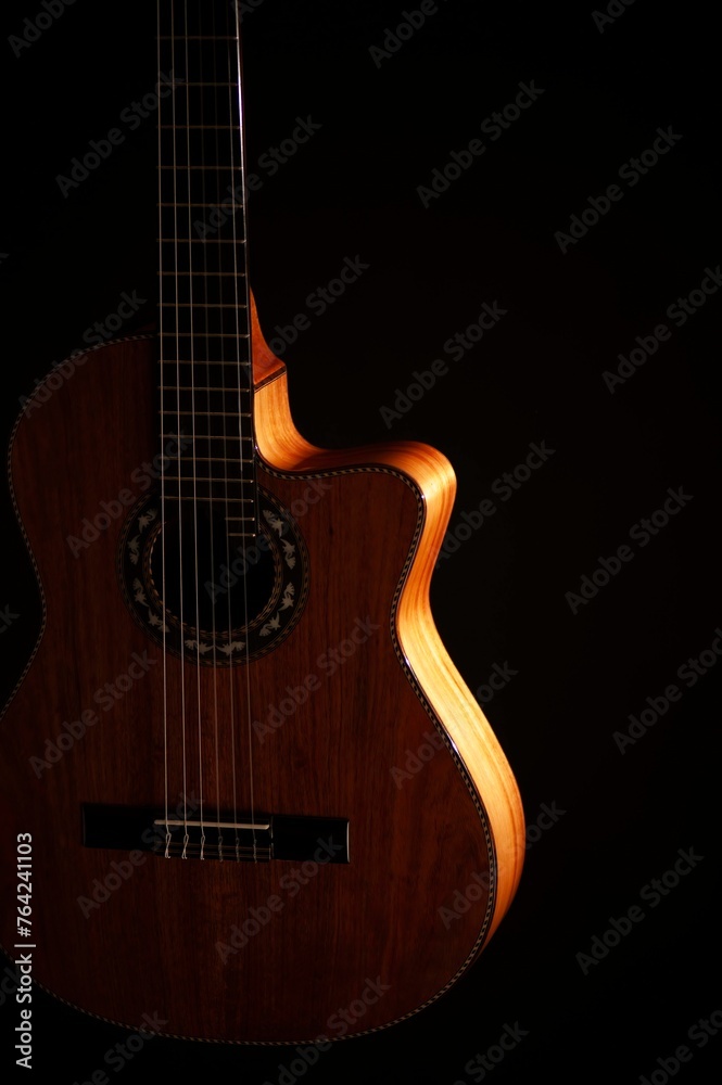 Obraz premium Classical Spanish flamenco guitar close up, dramatically lit isolated on black background with copy space.