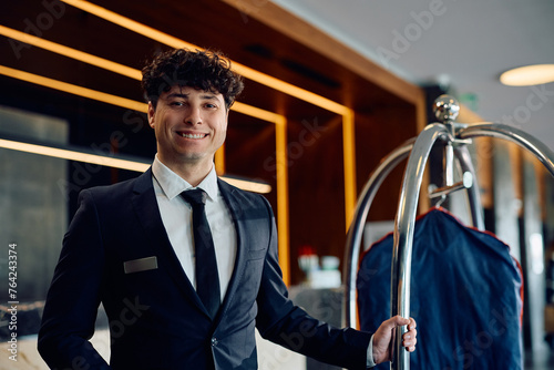 Fotografija Young happy bellboy working in  hotel and looking at camera.