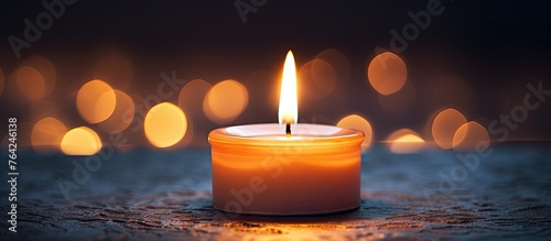 A glowing candle on a table with soft background lights