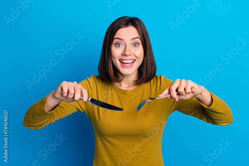 Photo of cheerful positive woman wear shirt holding utensils cutting meal isolated blue color background