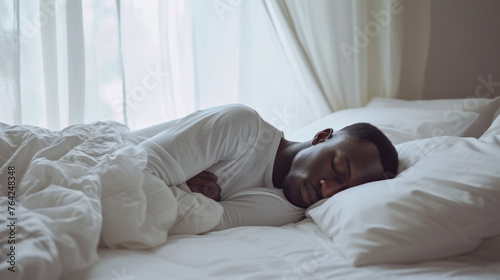 A 30-year-old man sleeps on a white bed.