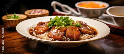 Bowl of tasty noodles with pork on a table