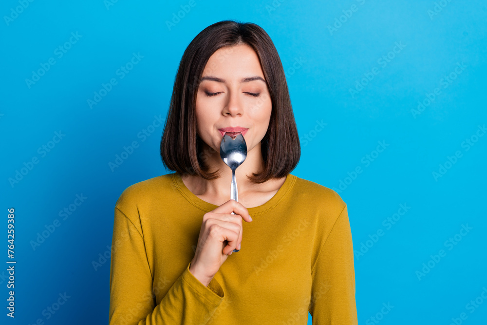 Photo of pretty cute woman wear shirt closed eyes licking spoon enjoying tasty dish isolated blue color background Photo of pretty cute woman wear shirt closed eyes licking spoon enjoying tasty dish isolated blue color background