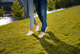 Cropped photo of two partners legs shadow footwear ad walking green grass fresh air free time outside