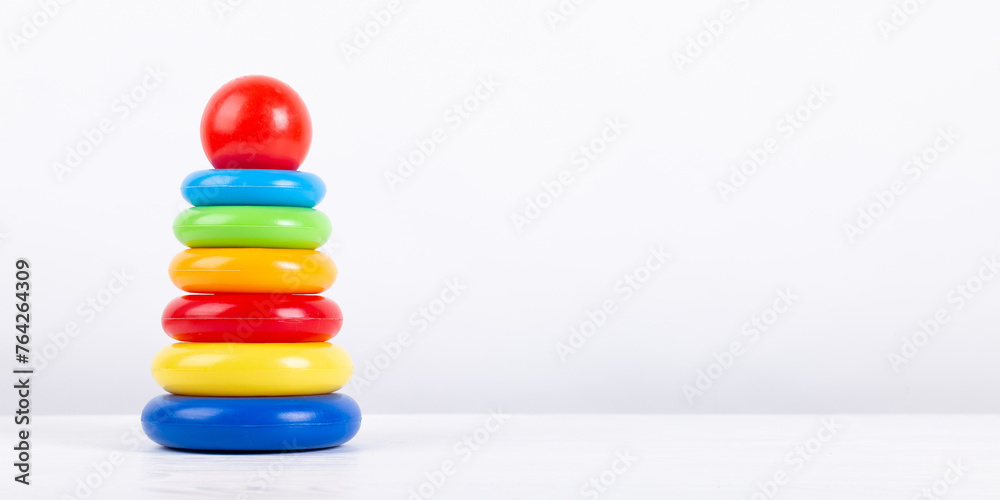 Children's colored pyramid on white background, copy space. Educational baby toy. Children's colored pyramid on white background, copy space. Educational baby toy.