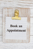Book an appointment on a wood clipboard with torn paper on wood desk