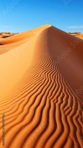 A vast sand dune dominates the scene under a clear blue sky