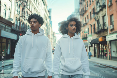 Two Afroamerican teenagers boys in blank hoodies walking in city street