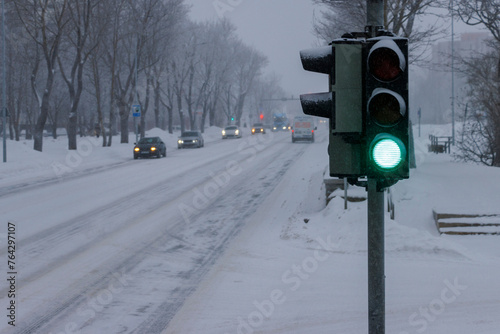 Winter bad weather condition. Traffic light on the street. Green light. Blurred background