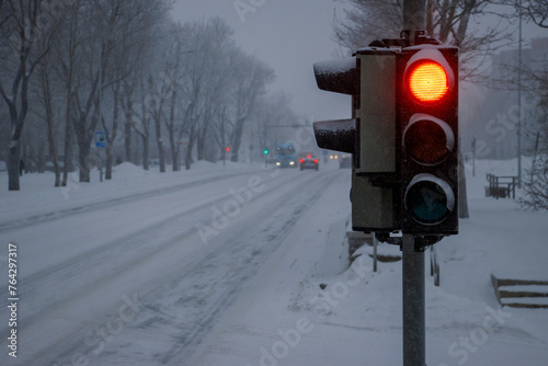 Winter bad weather condition. Traffic light on the street. Red light. Blurred background