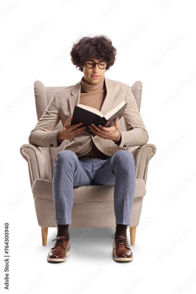 Young man sitting in an armchair and reading a book