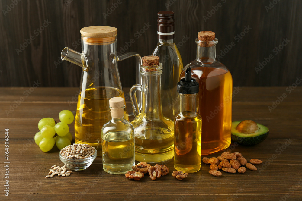 Vegetable fats. Different oils in glass bottles and ingredients on wooden table Vegetable fats. Different oils in glass bottles and ingredients on wooden table