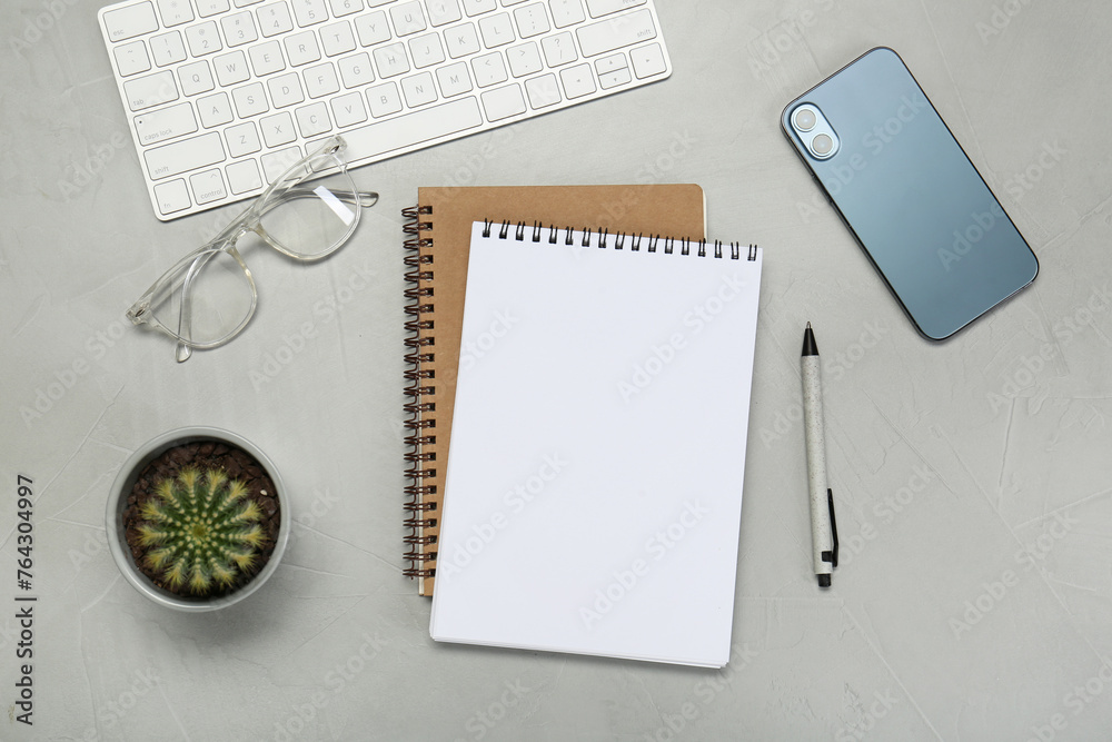 Flat lay composition with notebooks, smartphone, glasses and pen on light grey table