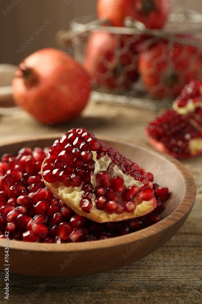 Ripe juicy pomegranate grains in bowl on wooden table, closeup Ripe juicy pomegranate grains in bowl on wooden table, closeup