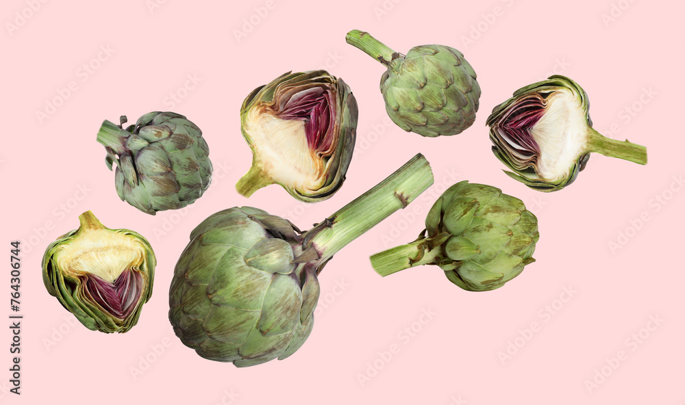 Fresh raw artichokes falling on pink background Fresh raw artichokes falling on pink background