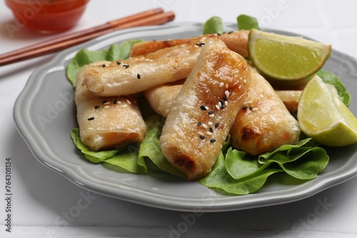 Tasty fried spring rolls served on light table, closeup
