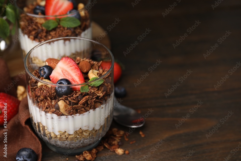 Tasty granola with berries, nuts, yogurt and chia seeds on wooden table, space for text