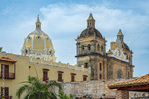 Cartagena, Colombia - July 25, 2023: Closeup, Santuario de San Pedro Claver church towers, historic front facade seen from Baluarte de San Ignacio bastion under blue cloudscape photo