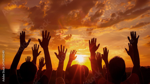 A group of people are holding hands and raising them in the air at sunset