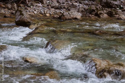 A stream of clean water running through some rocks in the river closeup. A crystal clear water in the forest stream up close shot.