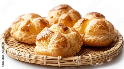 A group of five whole golden profiteroles baked and served on a bamboo plate, isolated against a photo