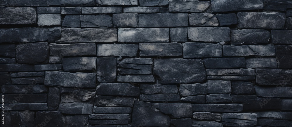 A detailed view of a solid black stone wall set against a plain black backdrop