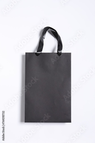 One black paper shopping bag on white background, top view