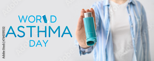 Woman holding asthma inhaler on light background, closeup