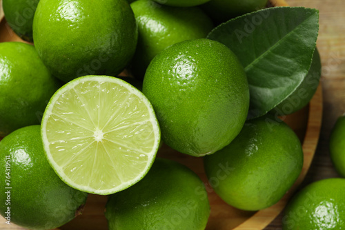 Fresh ripe limes and green leaf on table, closeup